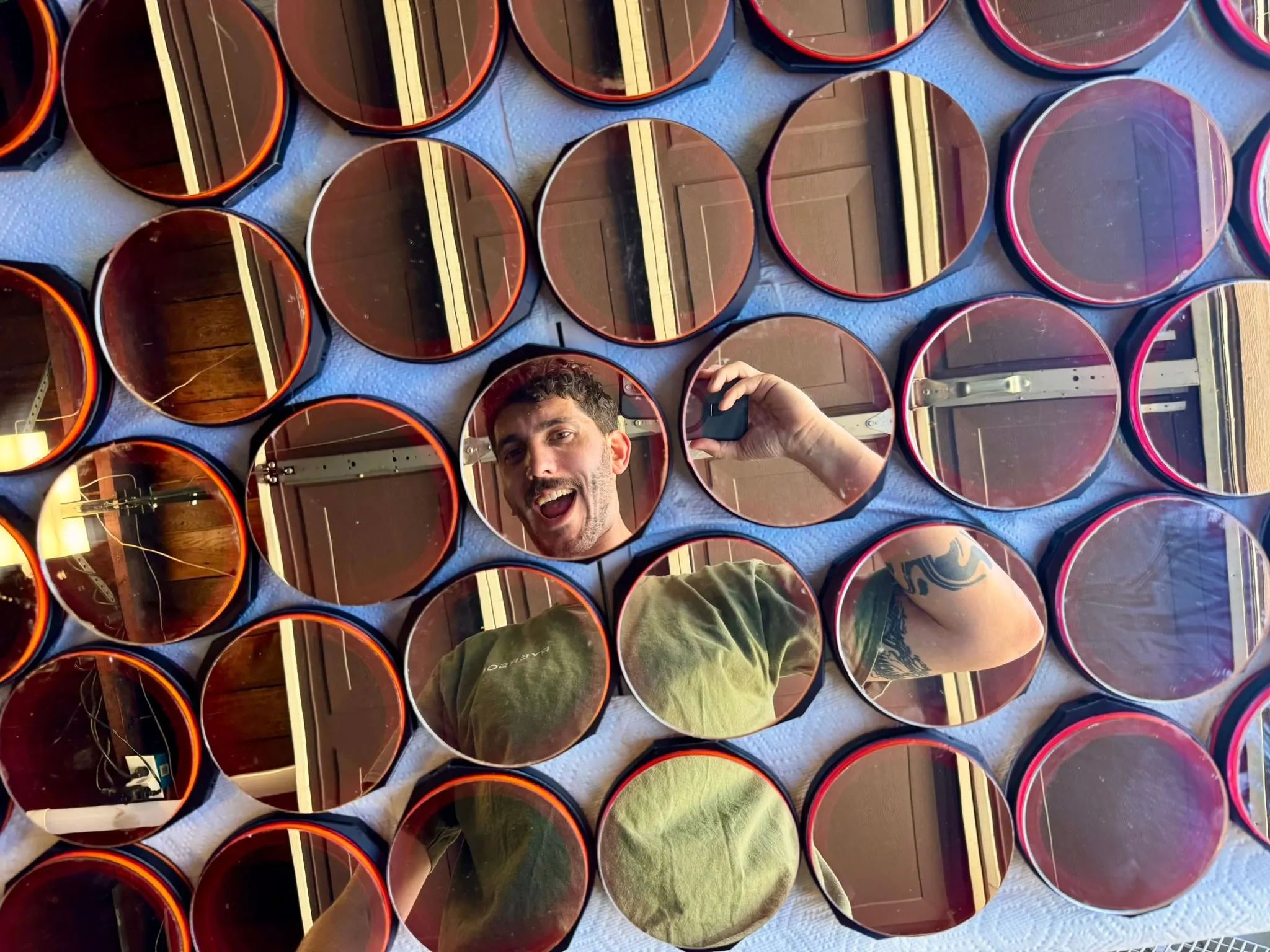 A grid of finished mirror modules reflecting Julien several times over