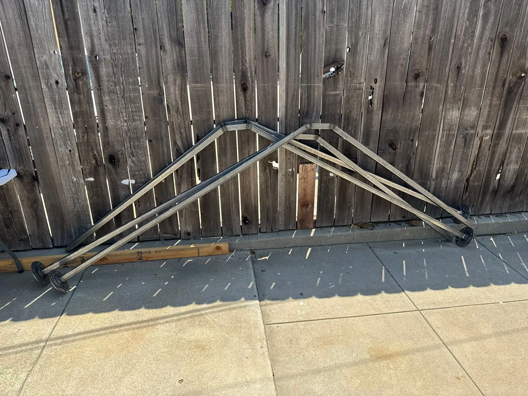 Four welded legs lined up against a wooden fence