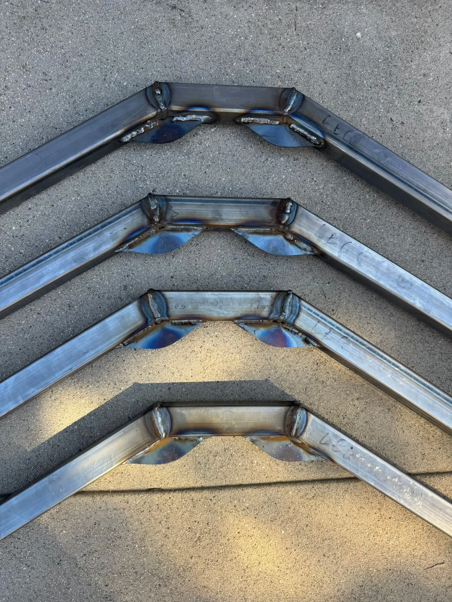 Four legs with gussets welded on, stacked on concrete