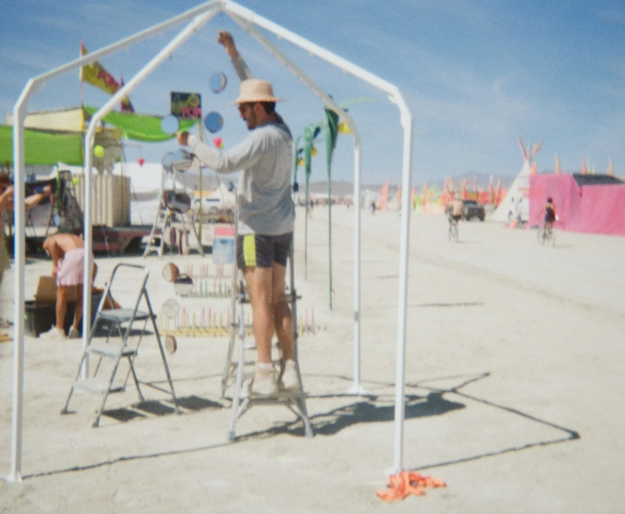 Julien on a stepladder clipping lines to the frame on playa
