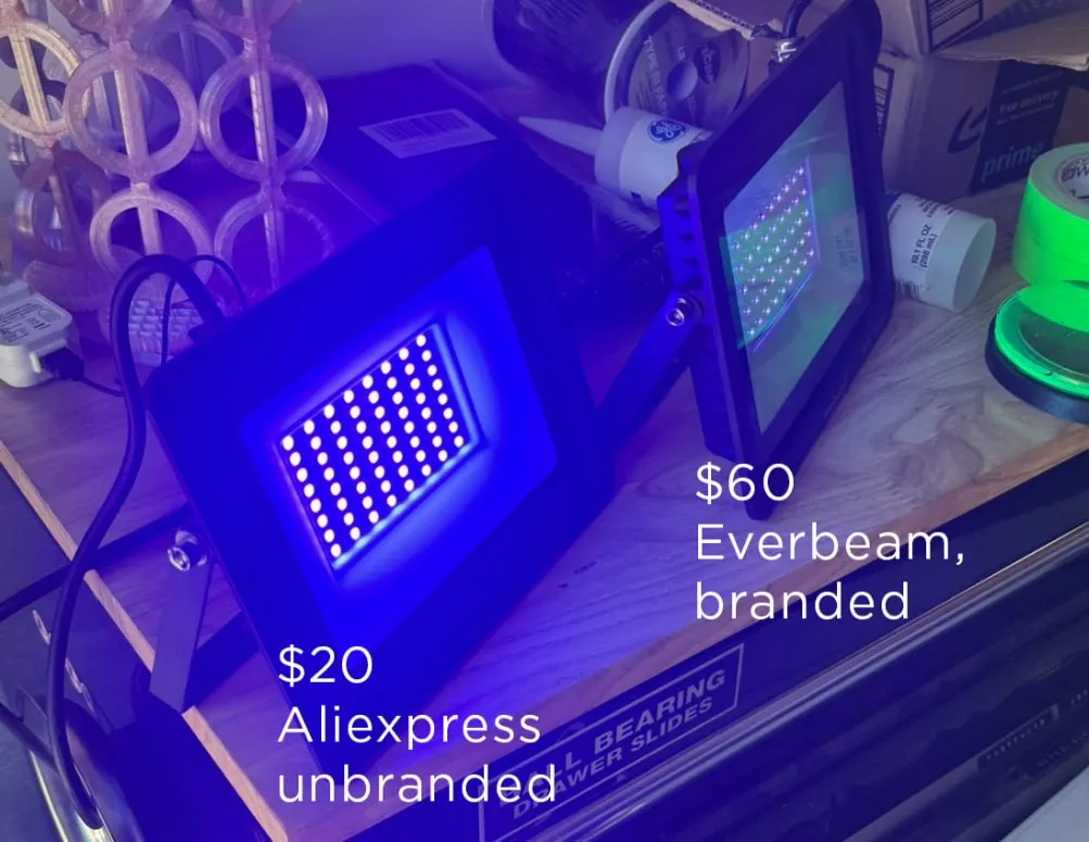 Two UV LED floodlights side by side on a workbench, labelled $20 AliExpress unbranded and $60 Everbeam branded