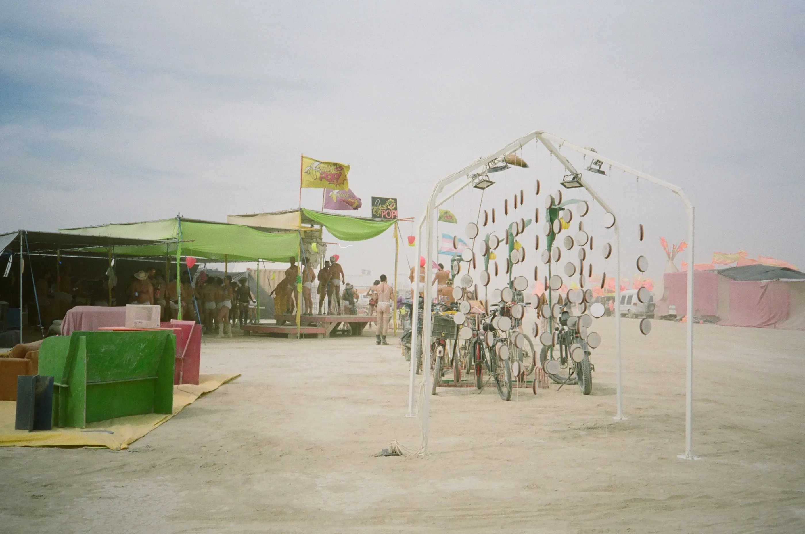 Film photo of the installation in daylight among camp shade structures